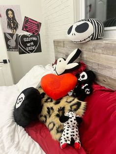 several stuffed animals are laying on a bed with red sheets and black and white pillows