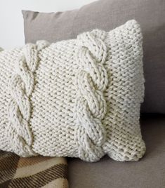 a white knitted pillow sitting on top of a couch