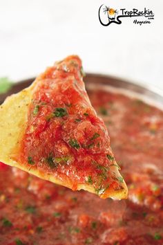 a tortilla chip being dipped with salsa