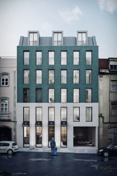 a person standing in front of a building with lots of windows on the side of it