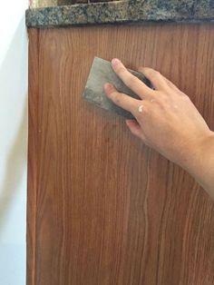 a person is cleaning a wooden door with a sponge