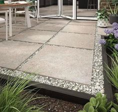 an outdoor patio area with gravel and plants on the ground, glass doors open to let in natural light