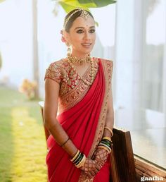 a woman wearing a red sari and gold jewelry