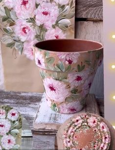 a flower pot sitting on top of a wooden table next to plates and a light