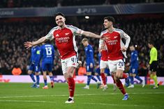 two soccer players are running on the field with their arms in the air as they celebrate