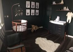 a baby's room with black walls and white rugs on the wooden floor