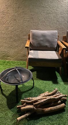 a fire pit sitting on top of a lush green field next to a wooden chair