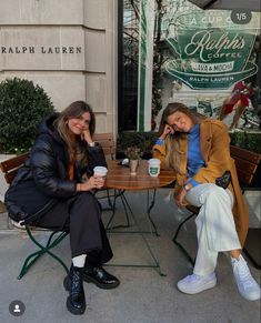 two women sitting at a table drinking coffee