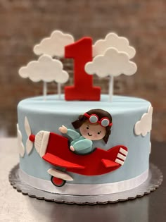 a blue and red birthday cake with a girl on it's airplane topper