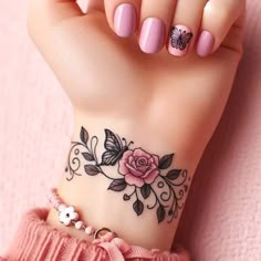 a woman's hand with a flower tattoo on her wrist and pink nail polish