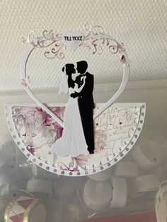 a paper cutout of a bride and groom in a heart shaped frame on top of a table