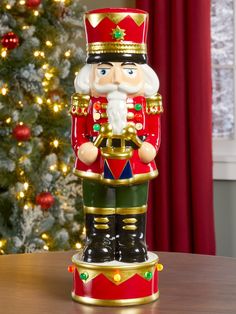 a nutcracker figurine on a table in front of a christmas tree