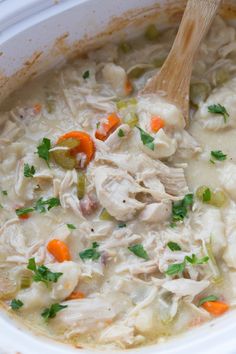 a bowl of chicken and dumpling soup with a wooden spoon in it, ready to be eaten