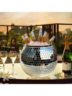 a disco ball filled with bottles of wine and ice in front of some glasses on a table