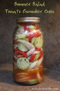 a mason jar filled with sliced cucumber and tomato slices, sitting on a counter