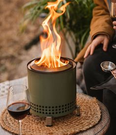 a person sitting at a table with a glass of wine in front of them and a fire pit