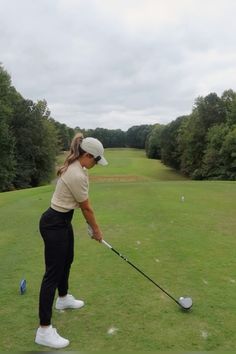 a woman hitting a golf ball with a club in her hand on a green course