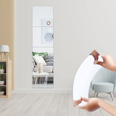 a woman is holding her hands up in front of a mirror with the reflection of a living room