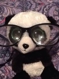 a stuffed panda bear wearing glasses on top of a bed