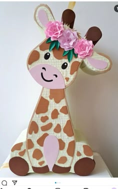 a giraffe with pink flowers on its head sitting on top of a table