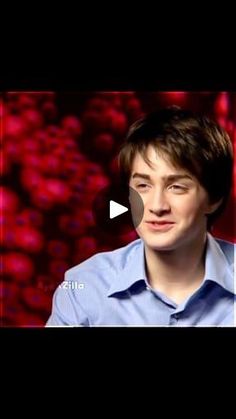 a young man in a blue shirt is talking to someone on the screen with red lights behind him