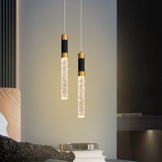 two lights hanging from the ceiling above a bed in a room with black and white walls