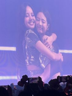 two women hugging each other in front of a crowd