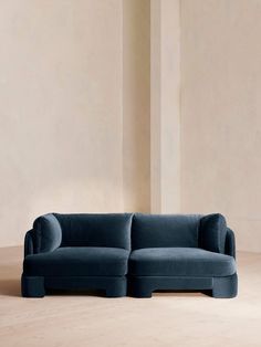 a blue couch sitting on top of a wooden floor next to a tall white wall