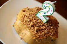 a piece of cake on a white plate with a candle in the shape of a number two