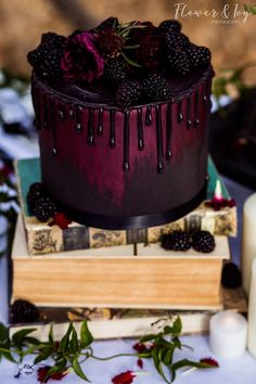 a chocolate cake with blackberries and roses on top is sitting next to some candles