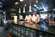 the chefs are preparing their meals in the restaurant's large kitchen area, which also features stainless steel appliances and black countertops