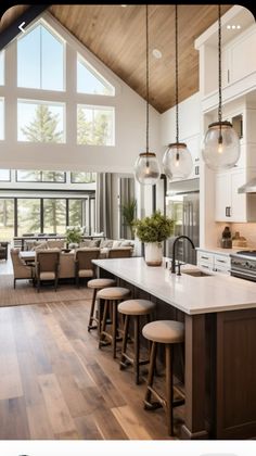 a large kitchen with an island in the middle and two stools at the end