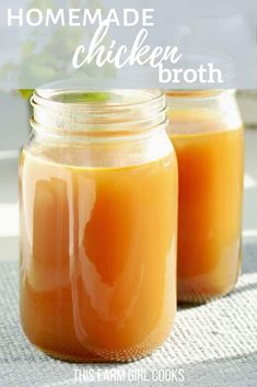 two jars filled with orange liquid sitting on top of a white cloth covered table next to a potted plant