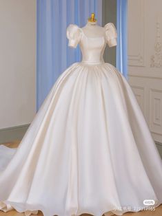 a white wedding dress on display in a room