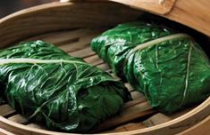 three pieces of green leafy food in a bamboo steamer