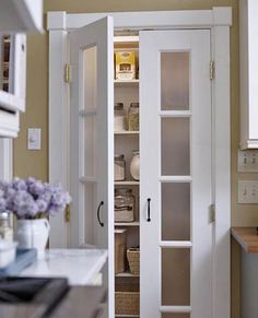 an open pantry door in a kitchen next to a counter top with baskets on it