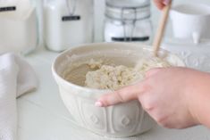 a person mixing food in a bowl with a wooden spoon