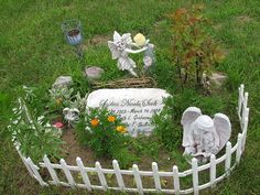 an angel statue in the middle of a garden with flowers and other decorations around it