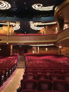 an empty auditorium with red seats and chandeliers