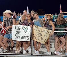 a group of young people holding signs in front of a fence at a sporting event