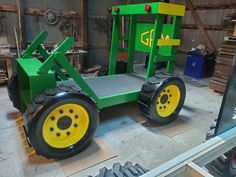 a green tractor with yellow wheels in a garage