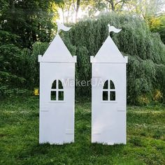 two white wooden buildings sitting on top of a lush green field