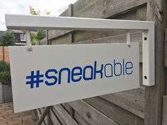 a white and blue sign that says snedokable hanging from the side of a wooden fence