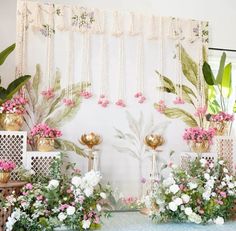 a table topped with lots of vases filled with flowers next to a white wall