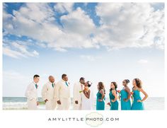 a group of people standing next to each other on top of a beach near the ocean