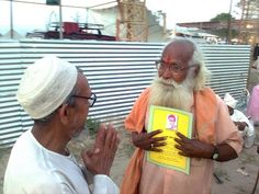 two men standing next to each other while one man holds up a book with his hands