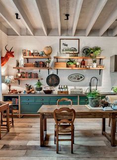 a kitchen filled with lots of wooden furniture and open shelving above a dining room table