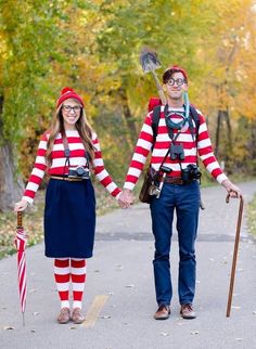 two people dressed in costumes holding hands and walking down a path with an american flag