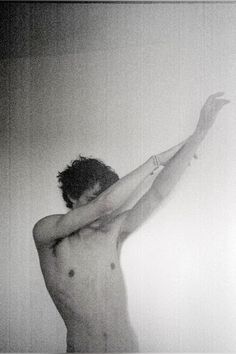 black and white photograph of a shirtless man with his arms stretched out in the air