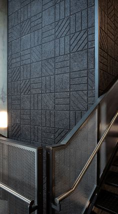 an escalator with metal railings next to a gray wall and light fixture